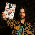 A photo of Liam Browne holding his book Dealer to Healer 